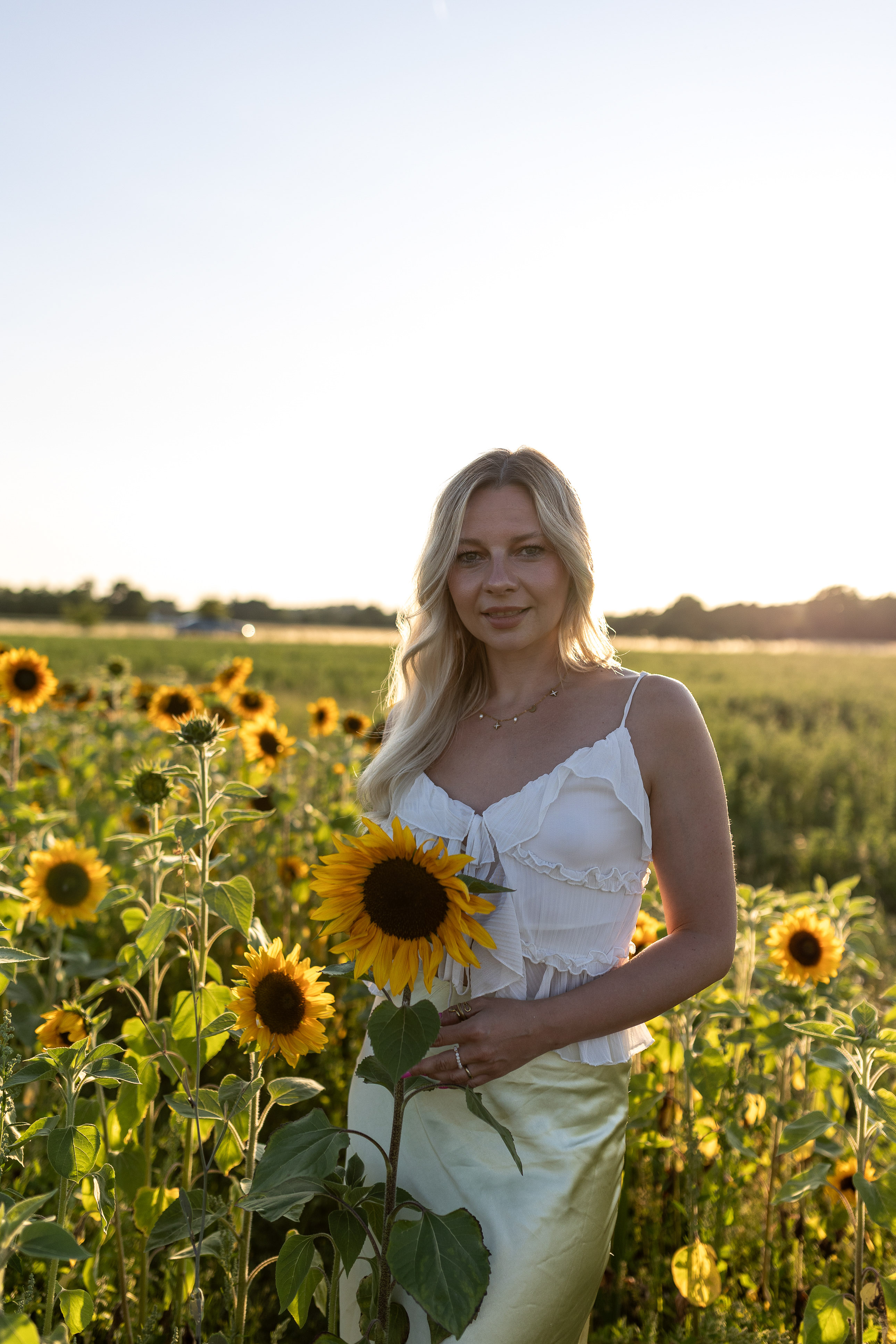 Portraitfoto einer Frau im goldenen Sonnenuntergangslicht im Sonnenblumenfeld Raum Erlangen