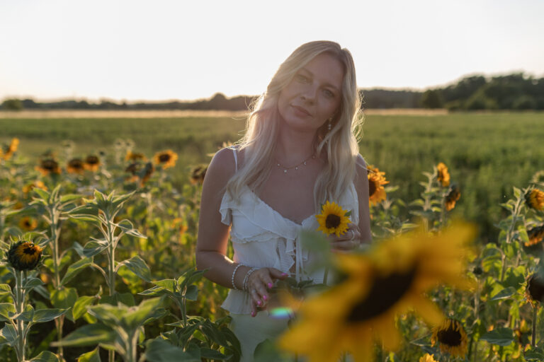 Portraitfoto einer Frau im goldenen Sonnenuntergangslicht im Sonnenblumenfeld Raum Erlangen