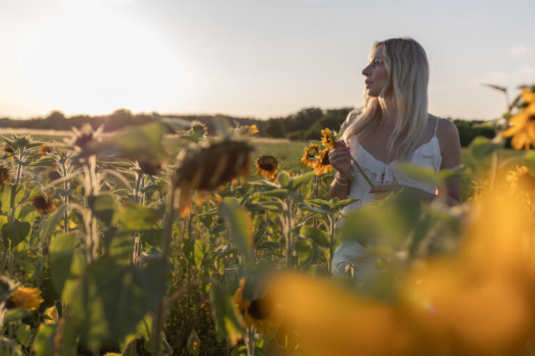 Portraitfoto einer Frau im goldenen Sonnenuntergangslicht im Sonnenblumenfeld Raum Erlangen